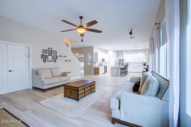 living room featuring a wealth of natural light, a ceiling fan, and light wood-style flooring