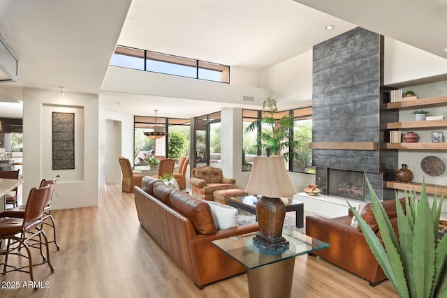 living room with light wood-type flooring and a tiled fireplace