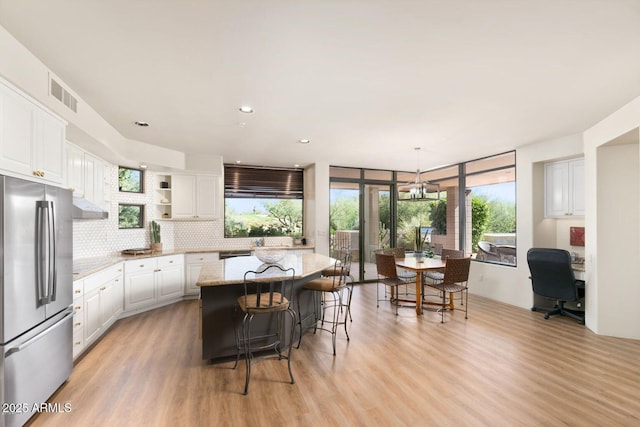 kitchen featuring open shelves, a center island, freestanding refrigerator, and white cabinets