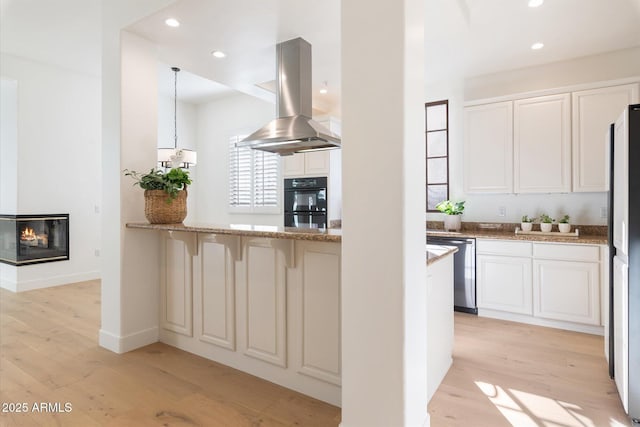 kitchen with white cabinets, stainless steel dishwasher, light wood-type flooring, and island range hood