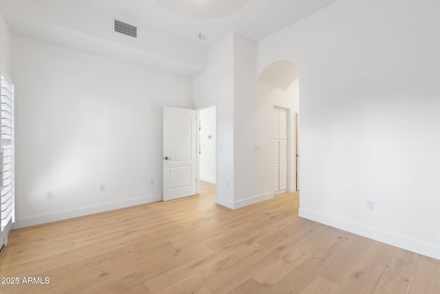 unfurnished room with a towering ceiling and light hardwood / wood-style floors