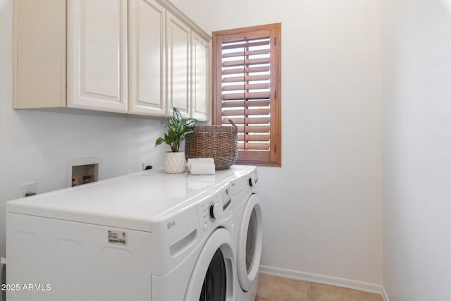 laundry area featuring washing machine and dryer, light tile patterned floors, and cabinets