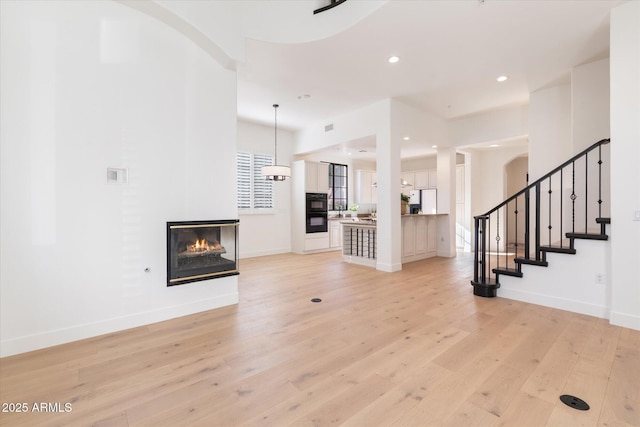 unfurnished living room with a multi sided fireplace and light wood-type flooring