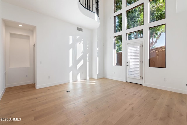 entrance foyer with a towering ceiling and light hardwood / wood-style floors