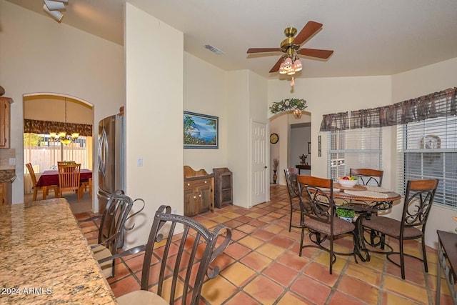 dining space with ceiling fan with notable chandelier, lofted ceiling, and light tile patterned flooring