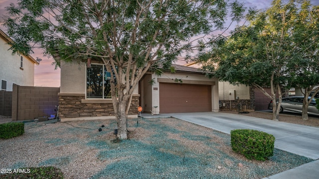 11742 W Chase Ln, Avondale, AZ 85323 - view of property hidden behind natural elements with stone siding, stucco siding, driveway, and an attached garage