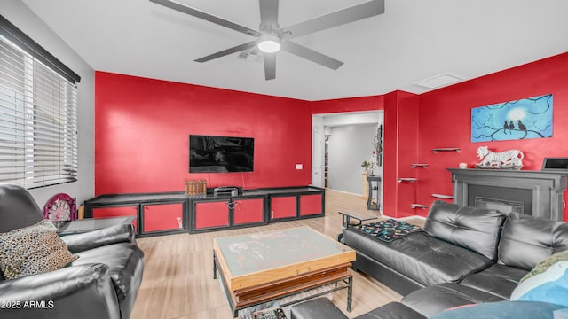 11742 W Chase Ln, Avondale, AZ 85323 - living room featuring an accent wall, wood finished floors, a ceiling fan, and a fireplace