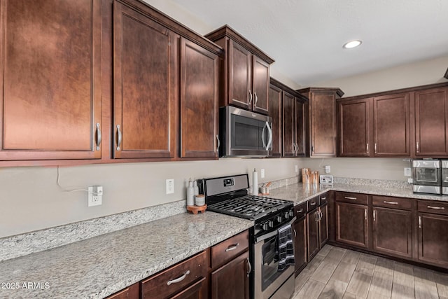 kitchen featuring dark brown cabinets, light stone countertops, and stainless steel appliances