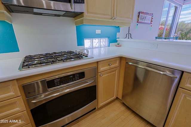 kitchen with light wood-style floors, stainless steel appliances, light countertops, and light brown cabinetry