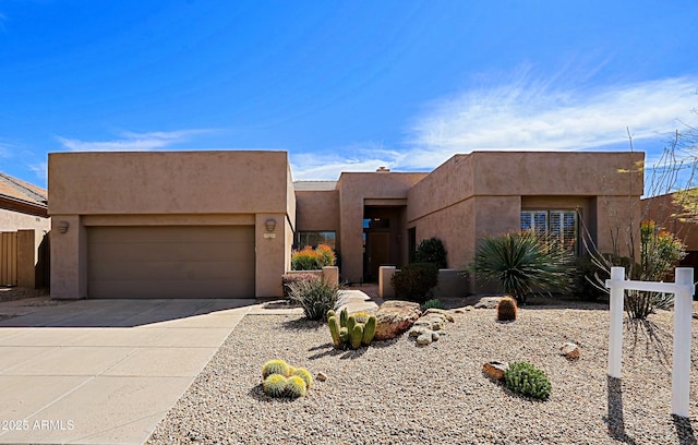 adobe home with an attached garage, concrete driveway, and stucco siding