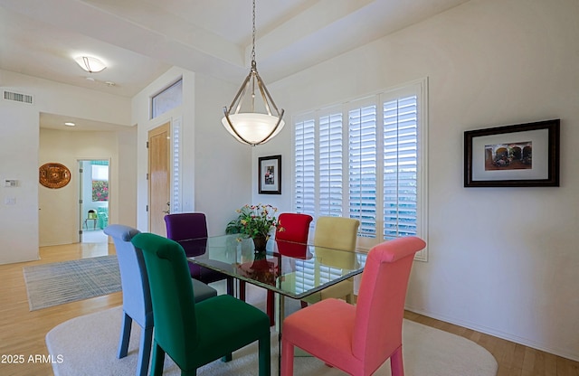 dining area featuring visible vents, baseboards, and wood finished floors