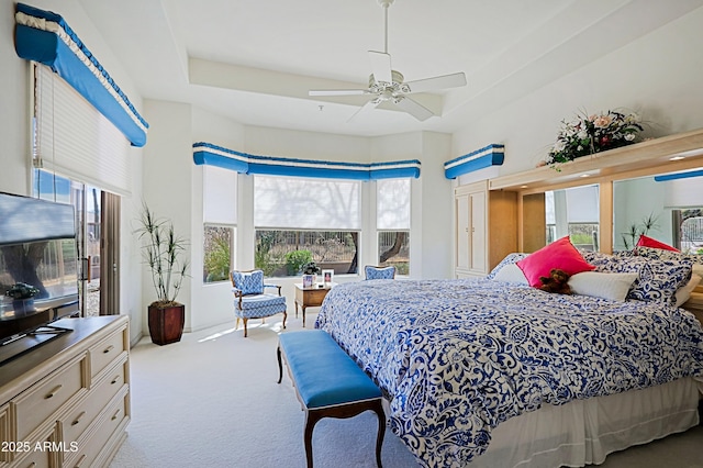 carpeted bedroom with a tray ceiling and a ceiling fan