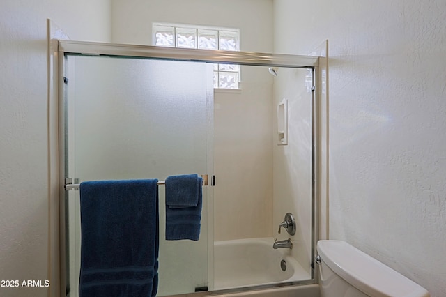 full bath with toilet, enclosed tub / shower combo, and a textured wall