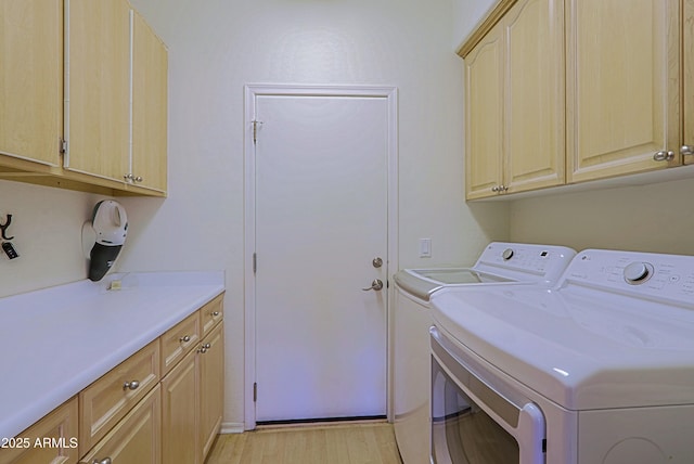 clothes washing area with cabinet space, light wood-style floors, and independent washer and dryer