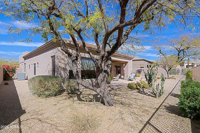 view of front of property with central AC, a patio area, a fenced backyard, and stucco siding