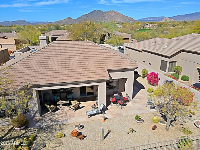 rear view of house with stucco siding, an outdoor hangout area, a patio area, a mountain view, and fence