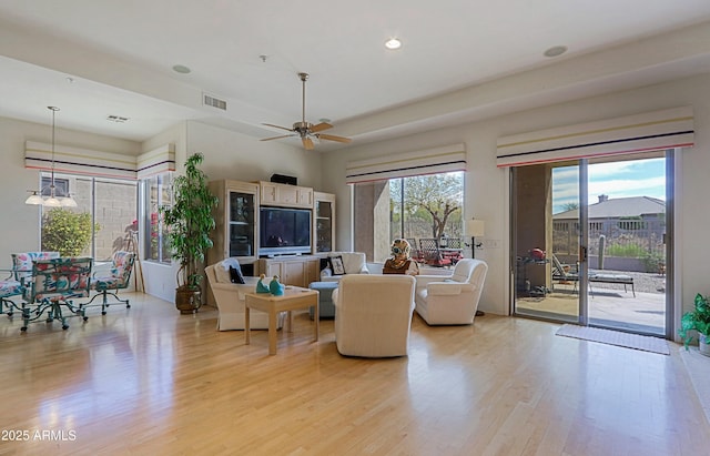 living area with light wood-type flooring, ceiling fan, visible vents, and recessed lighting