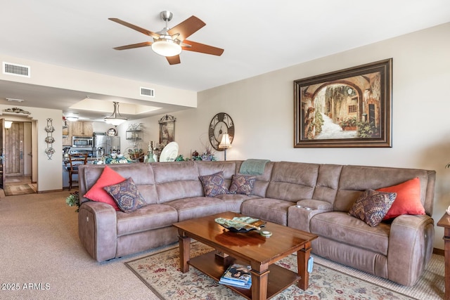 living area featuring visible vents, light colored carpet, and a ceiling fan