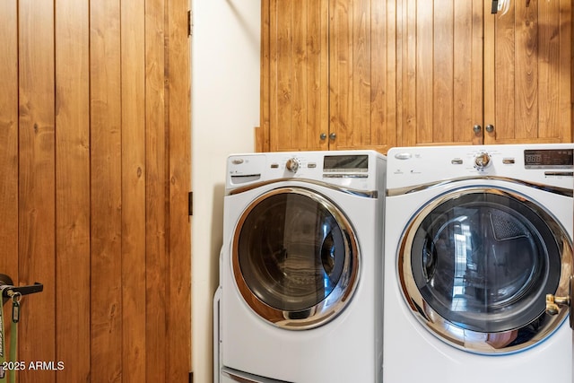 clothes washing area featuring cabinet space and washing machine and clothes dryer