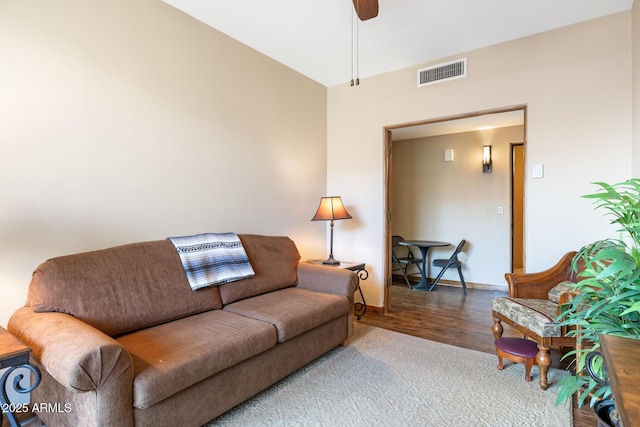 living room with wood finished floors, baseboards, visible vents, and ceiling fan