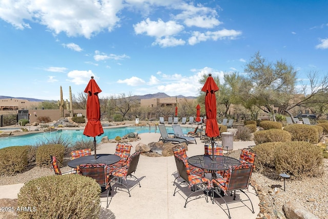 community pool featuring a patio, outdoor dining area, fence, and a mountain view