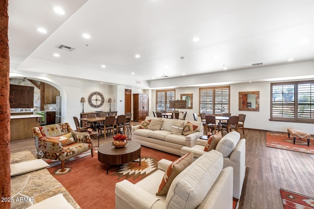 living area featuring arched walkways, visible vents, recessed lighting, and wood finished floors