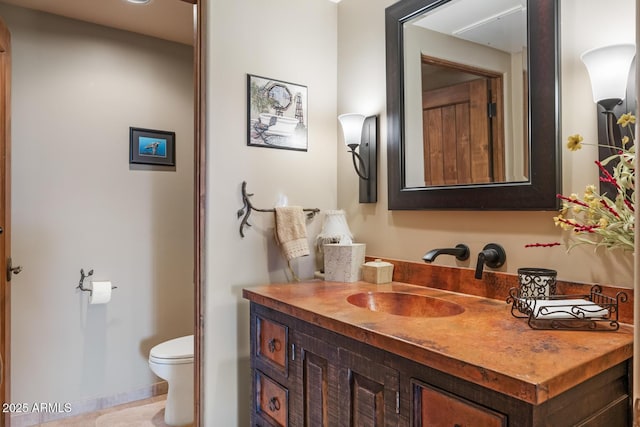 bathroom featuring baseboards, toilet, and vanity