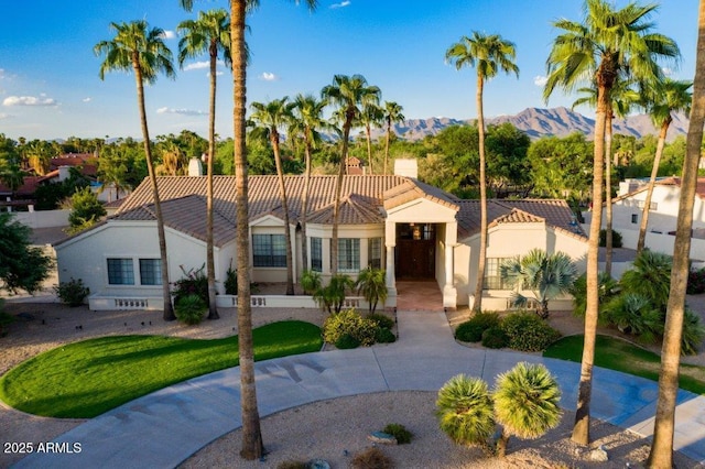 mediterranean / spanish house featuring a tile roof, stucco siding, a mountain view, and fence