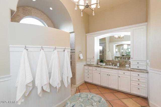 bathroom featuring an inviting chandelier, tile patterned floors, vaulted ceiling, and vanity