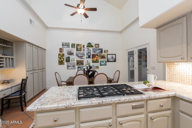 kitchen featuring cream cabinets, stainless steel gas cooktop, a peninsula, visible vents, and backsplash