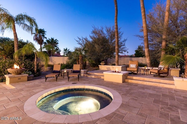 view of patio with a fire pit, an in ground hot tub, and fence