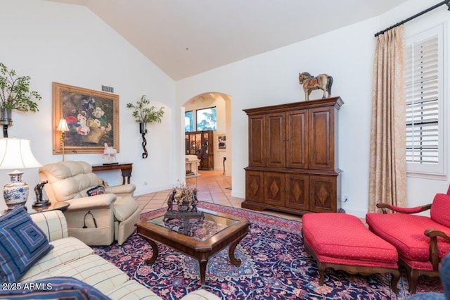 living area with arched walkways, vaulted ceiling, a wealth of natural light, and light tile patterned flooring