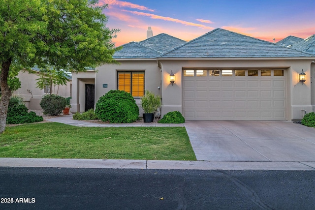 view of front of home featuring a garage, a lawn, concrete driveway, a high end roof, and stucco siding