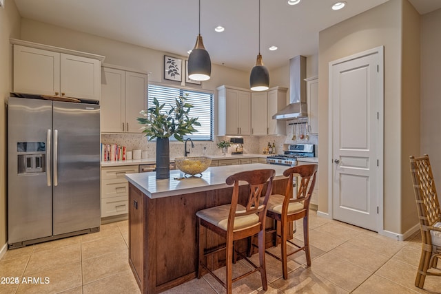 kitchen featuring appliances with stainless steel finishes, light countertops, wall chimney range hood, and light tile patterned floors