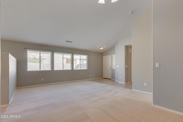 carpeted spare room with a wealth of natural light and lofted ceiling