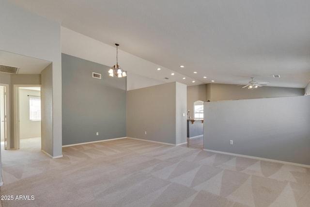 carpeted empty room featuring ceiling fan with notable chandelier and vaulted ceiling