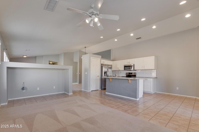 kitchen featuring appliances with stainless steel finishes, white cabinetry, decorative backsplash, ceiling fan, and light tile patterned floors