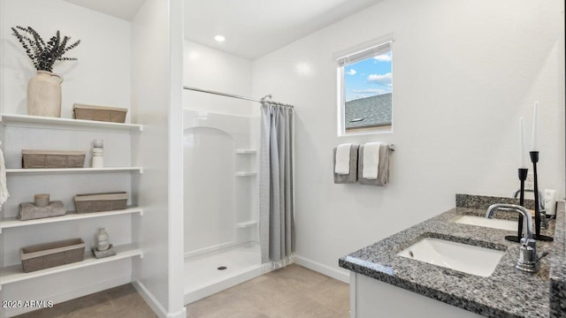 bathroom with double vanity, baseboards, tile patterned floors, a shower stall, and a sink