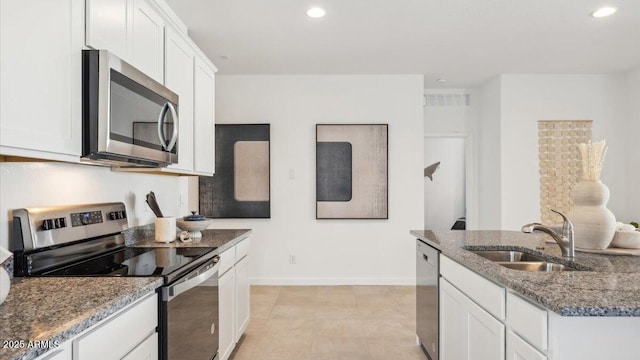 kitchen with white cabinetry, stainless steel appliances, a sink, and dark stone counters