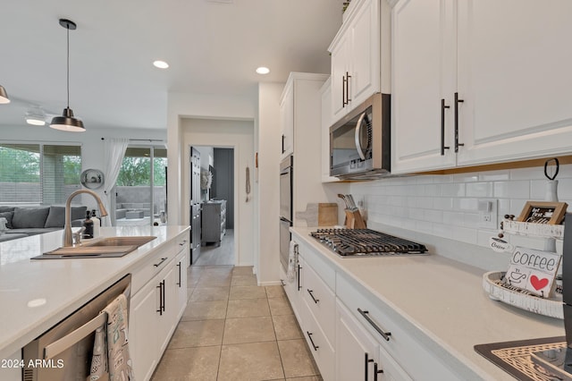 kitchen featuring sink, hanging light fixtures, light tile patterned floors, stainless steel appliances, and white cabinets