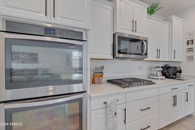 kitchen with backsplash, appliances with stainless steel finishes, light tile patterned floors, and white cabinets