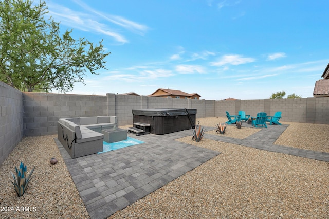 view of patio with a hot tub and an outdoor living space with a fire pit