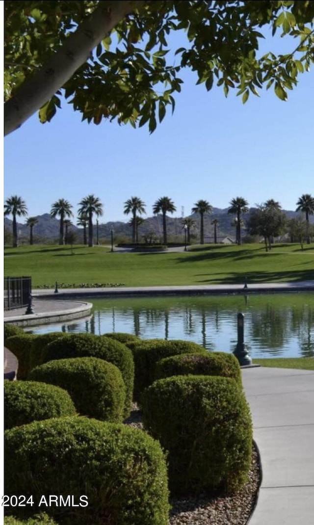 view of home's community with a water view and a lawn