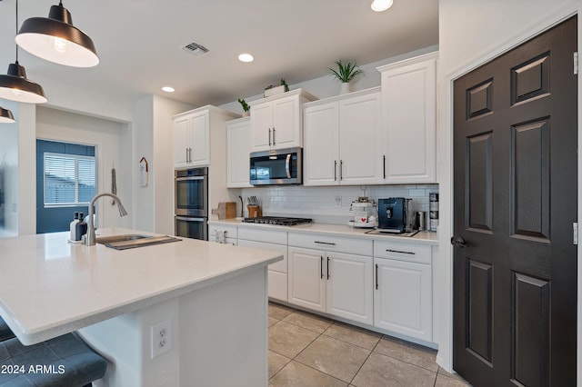 kitchen featuring sink, white cabinets, backsplash, hanging light fixtures, and stainless steel appliances