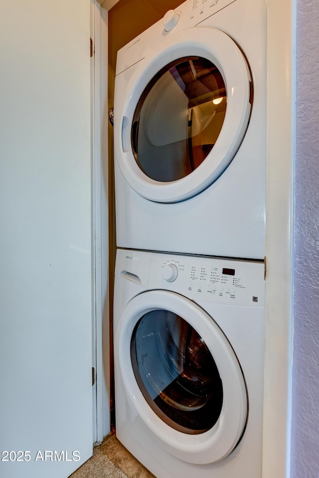washroom featuring stacked washer / drying machine and laundry area