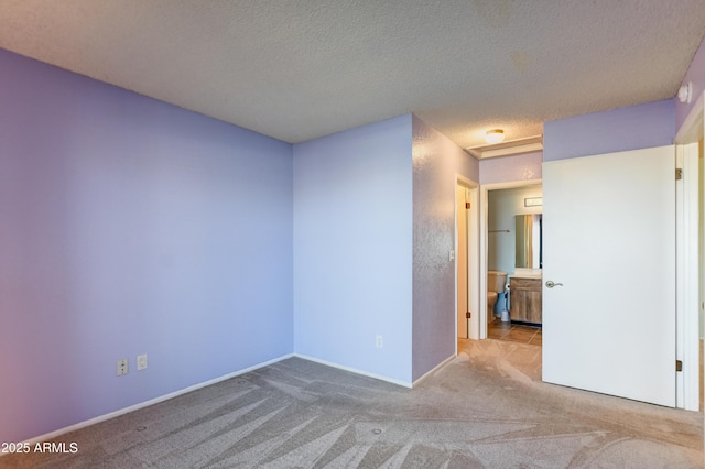 carpeted empty room with baseboards and a textured ceiling