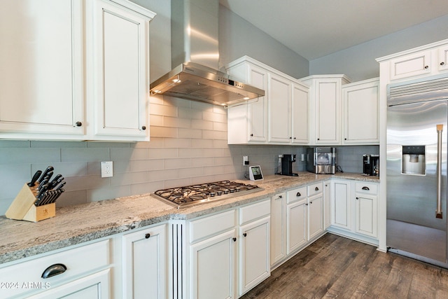 kitchen featuring white cabinetry, wall chimney exhaust hood, dark hardwood / wood-style flooring, backsplash, and appliances with stainless steel finishes