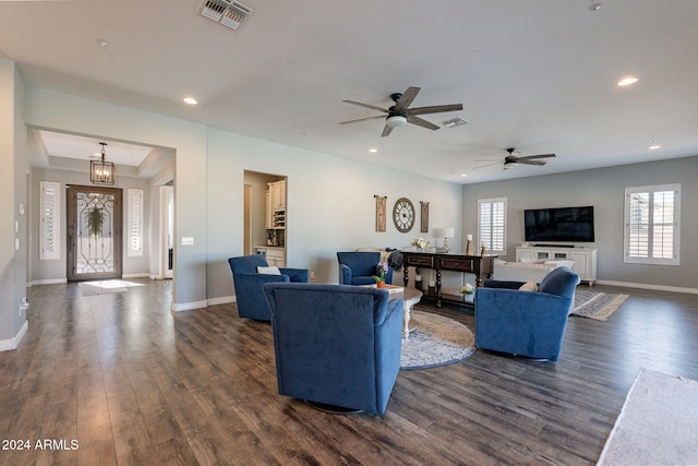 living room with dark wood-type flooring and ceiling fan with notable chandelier