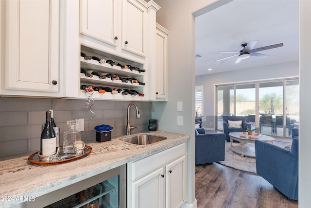 bar with light stone countertops, dark hardwood / wood-style flooring, backsplash, and sink