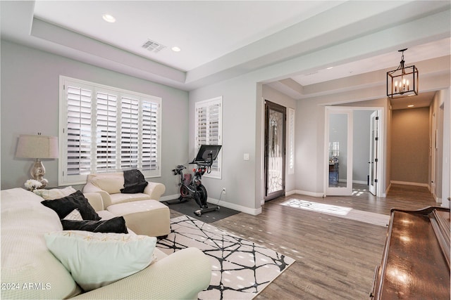 living room featuring a chandelier, wood-type flooring, french doors, and a tray ceiling